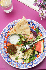 Summer arabic salad with falafel, hummus, water melon, carrots, lettuce, carrots, dressing and pita bread  - 615535281