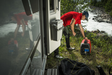 Man Firing Up Gas Powered Portable Inverter Generator To Hook Up His Camper Van - obrazy, fototapety, plakaty