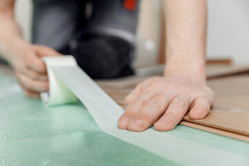 Professional builder use spreads underlayment for laying laminate flooring in white room