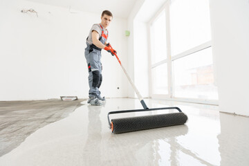 Master with needle roller for new screed concrete with mixture of cement for leveling for floors....