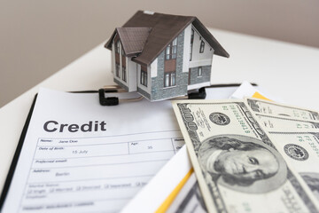 House model and Money, house key lying on real estate contract, home loan and investment concept.