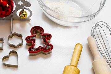 Kitchen white table with wooden rolling pins, bowl of flour, Christmas toys. The concept of a family making holiday cookies.