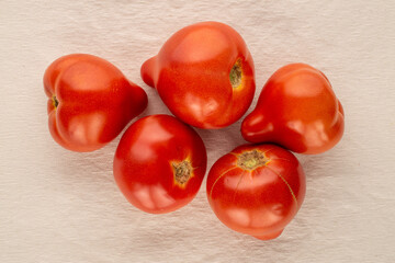 Several red tomatoes on a linen cloth, macro, top view.