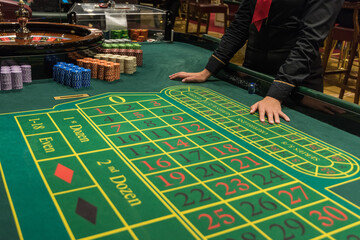 Casino, gambling and entertainment concept - roulette table and stack of poker chips