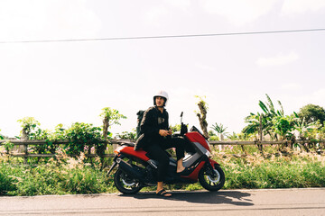 Fototapeta premium Man on motorbike with smartphone in Bali