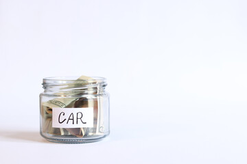 Glass jar with money close-up on a white background. Piggy bank with dollars for the car. Save money for the future