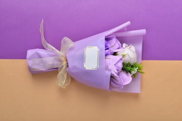 Bouquet of flowers wrapped in purple paper and tied with a ribbon on a colorful background