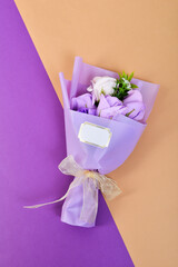 Fototapeta premium Bouquet of flowers wrapped in purple paper and tied with a ribbon on a colorful background