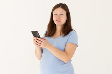 Portrait of a smiling cute pregnant woman using mobile phone isolated on a white background