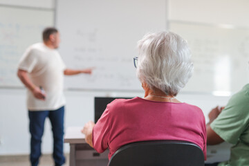elderly student sitting in the classroom paying attention to the teacher during math class at a...
