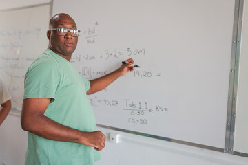 estudante Brasileiro negro careca resolvendo na lousa o problema de matemática passado pelo...