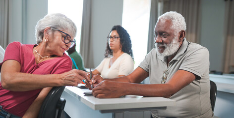 senhora idosa aluna de uma turma para adultos no Brasil conversando com seu colega de classe...