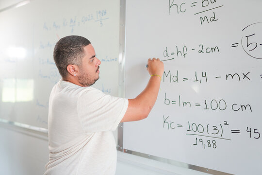 professor Brasileiro passando a resolu&ccedil;&atilde;o da li&ccedil;&atilde;o de de casa que passou para seus alunos em um curso para adultos em uma escola no Brasil