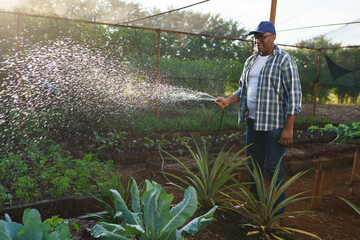 small Latin farmer watering his garden with a hose in a small rural property in Brazil