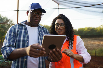 Farmer and technician reviewing a tablet together in a cultivated field © Nexa