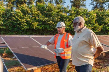 Latin farmer talking with the technician who installed photovoltaic panels on his farm in Brazil