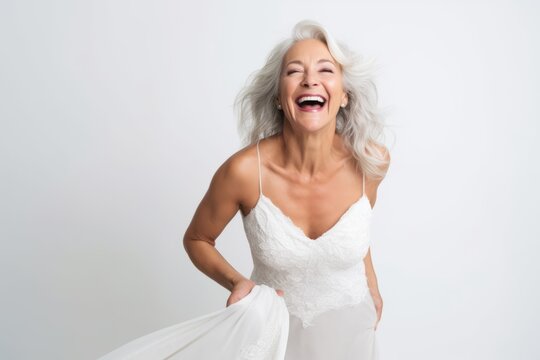 Portrait of happy mature woman in white wedding dress laughing over white background