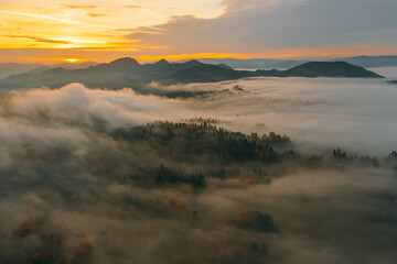 Sunny sunrise in autumn mountains. Mountains in a fog illuminated by rising sun. Autumn landscape with vivid sunlight. 