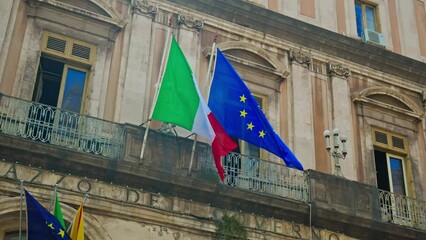 Historical buildings with flags on Via Etnea in Catania, Italy. View of the main street of the historical center of Catania, Sicily.