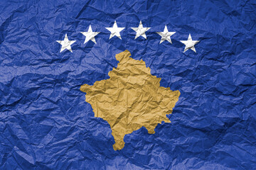 Flag of Kosovo on crumpled paper. Textured background.