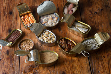 top view of a set of cans with fish and seafood on wooden background