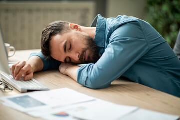 Portrait Of Tired Young Office Employee Sleeping At Workplace - obrazy, fototapety, plakaty