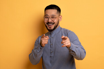 Gotcha. Cheerful Handsome Asian Man Poiting At Camera With Two Hands