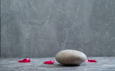 gray background with rose petals and gray zen stone