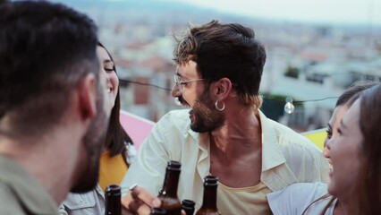 Group of cheerful best friends on a rooftop wine party. Crowd of young people drinking, toasting glasses, laughing and having fun on a friendly meeting, enjoying happy hour at winery bar restaurant