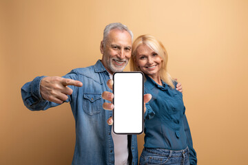 Happy senior couple showing phone with white empty screen