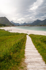Sandy beach with path, sea bay with coast with mountains - Ramberg beach, Lofoten, Norway