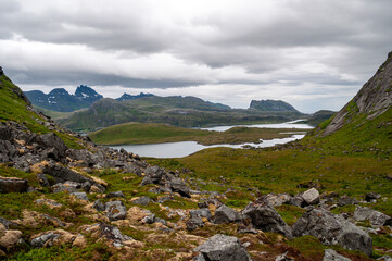Mountains with lakes and a meadow full of big stones - Lofoten, Norway