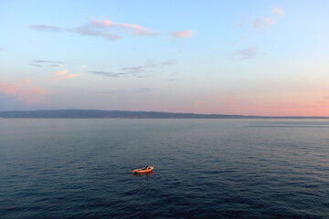 Beautiful sunset over the Adriatic Sea. Small old fashioned fishing boat at the sea. 