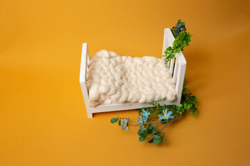 baby bed on with green leaves on a yellow background. bed for a photo session of a newborn. small bed. bed for dolls