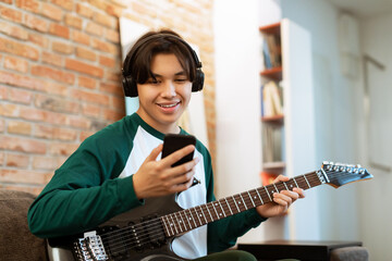 Japanese Guy Plays Electric Guitar Watching Tutorial on Cellphone Indoor