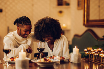 Fototapeta na wymiar African american couple having romantic date and drinking wine at home
