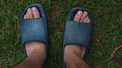 pies de adulto joven con sandalias y uñas pintadas en el jardin