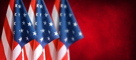 Three American flags in front of red blurred background