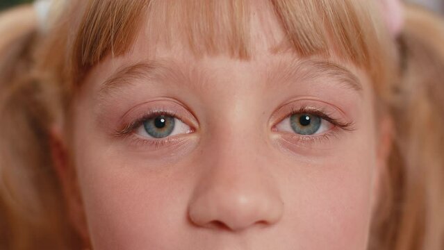 Extreme close-up macro portrait of smiling girl face. Teen beautiful kid's eyes looking at camera. Young positive toddler child opening wide her closed eyes. Gray eyes of blonde female children model