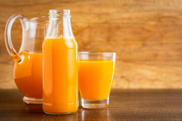 A glass bottle of fruit juice. Orange  juice on wooden table.
