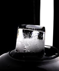 Ice cube on black background. Low key photo.