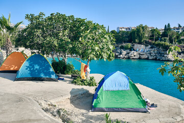 Tourist tents on a cliff in sea lagoon. Summertime camping at seaside. Summer campground