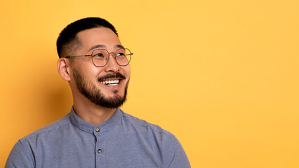 Handsome Asian Man In Eyeglasses Looking Aside At Copy Space With Interest