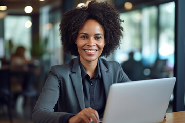 Fototapeta premium Black woman professional working on a laptop in an office setting, dressed in formal attire. The focus and expertise on the girl's face, coupled with the clean and modern. Generative AI Technology.