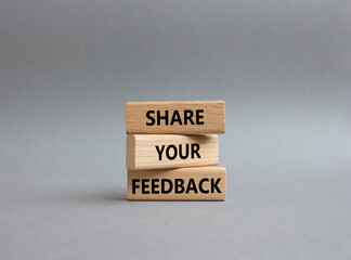 Feedback symbol. Concept word Share your feedback on wooden blocks. Beautiful grey background....