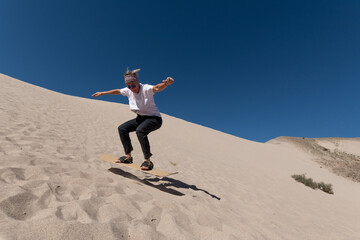 Fototapeta premium 55 year old woman gliding across the sand on a sandboard