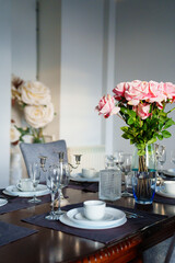 A beautiful table served with dishes and a bouquet of roses. 