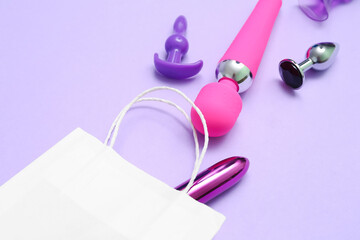 Shopping bag with sex toys on lilac background, closeup