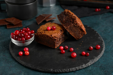 Board with pieces of tasty chocolate brownie on black background