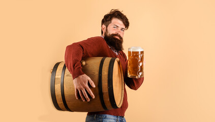 Beer time. Attractive bearded male brewer with mug of beer and wooden barrel beer. Holiday, drinks,...